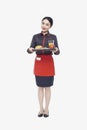 Young Waitress carrying tray with food, studio shot Royalty Free Stock Photo