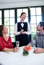 Young waitress laughing while taking an order from a couple Royalty Free Stock Photo