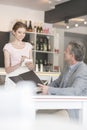 Young waitress taking order from mature customer at restaurant Royalty Free Stock Photo