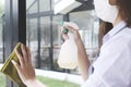 Young waitress with face mask disinfecting restaurant tables