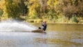 Young wakeboarder surfing along the river