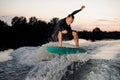 Young wakesurfer in black swimsuit jumping on a wake board Royalty Free Stock Photo