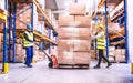 Warehouse workers pulling a pallet truck.