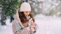 A young warmly dressed woman holds a cup of hot drink in her hands in a winter park. Royalty Free Stock Photo