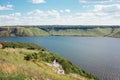 Young wedding couple of groom and bride in white dress walking holding hands on the hill near the beautiful lake. Scenic landscape Royalty Free Stock Photo