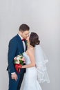 Young wedding couple kissing against a gray wall