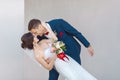 Young wedding couple kissing against a gray wall