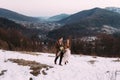 Young wedding couple running, having fun holding hands at ski resort village with wooden cottages near logs. Winter Royalty Free Stock Photo