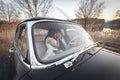 Young wedding couple sitting smiling inside retro car and are kissing each other. just married embrace is hugging inside car. brid Royalty Free Stock Photo