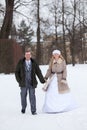 Young wedding couple walking in snowy winter park, bride and groom hold hands Royalty Free Stock Photo