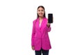 young well-groomed smiling brunette successful boss woman dressed in a pink jacket shows a smartphone with a mockup