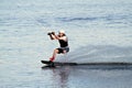 A young wet man wake boarding on a lake in summertime