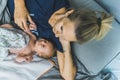 Young white blond mother in bed cuddling with her newborn baby boy touching his hand. Motherhood. Calmn and cozy