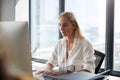Young white blonde woman sitting at a desk working at a computer in a creative office, close up Royalty Free Stock Photo