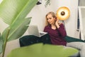Young white blonde woman sitting on green couch in living room holding and looking at laptop computer. Indoor shot. Royalty Free Stock Photo