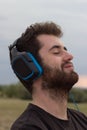 Young white boy with curly hair listening to music in the field. Smiling expression Royalty Free Stock Photo