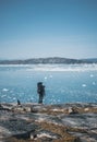 Young white caucasian man with backpack on a hiking trip in Greenland overlooking Atlantic ocean with icebergs. Arctic Royalty Free Stock Photo