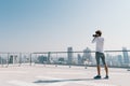 White man taking cityscape photo on building rooftop on sunny day. Photography hobby, gadget technology, leisure activity concept