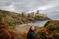 Young white Caucasian woman with long red hair stands against the background of the famous medieval castle la Latte of the fortres Royalty Free Stock Photo