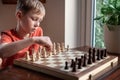 Young white child playing a game of chess on large chess board. Chess board on table in front of school boy thinking of next move Royalty Free Stock Photo