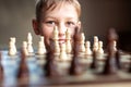 Young white child playing a game of chess on large chess board. Chess board on table in front of school boy thinking of next move Royalty Free Stock Photo