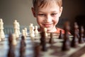 Young white child playing a game of chess on large chess board. Chess board on table in front of school boy thinking of next move Royalty Free Stock Photo