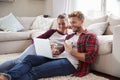 Young white couple sitting on the floor at home using laptop Royalty Free Stock Photo