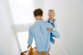 Young white father going down on stairs with little daughter at home