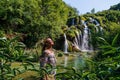 Young white female tourist smiling looking at the sun on the background of the beautiful Plitvice complex waterfall Royalty Free Stock Photo