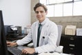 Young white male doctor using computer smiling to camera Royalty Free Stock Photo