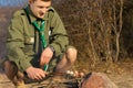 Young White Male Scout Cooking Sausages on Ground