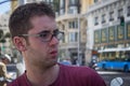 Young white man with curly hair and glasses on a city street. Expression worried. Royalty Free Stock Photo