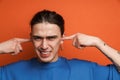 Young white man with earring frowning and plugging his ears Royalty Free Stock Photo