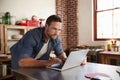Young white man shopping on-line in kitchen, close up Royalty Free Stock Photo