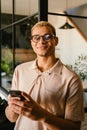 Young man smiling and holding cellphone while working in office Royalty Free Stock Photo