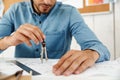 Young white man using compass working with drawings in office Royalty Free Stock Photo