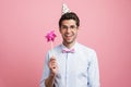 Young white man wearing party cone posing with flower wind spinner