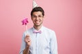 Young white man wearing party cone posing with flower wind spinner