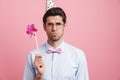 Young white man wearing party cone posing with flower wind spinner