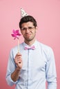 Young white man wearing party cone posing with flower wind spinner