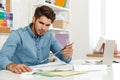 Young white man working with laptop and drawings in office Royalty Free Stock Photo