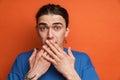 Young white surprised man with earring covering his mouth