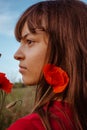 A young white teen girl portrait close-up in profileon nature meadow with red blooming poppies flowers bouquet Royalty Free Stock Photo