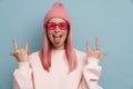 Young white woman gesturing horns sign and sticking out her tongue Royalty Free Stock Photo