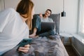 Young white woman holding cellphone while man using laptop in bed Royalty Free Stock Photo