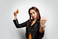 A young white woman in a leather jacket holding chicken eggs in her hand and showing her fist. Copy space. Feminism, girl power,