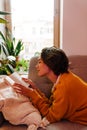 Young white woman reading book while lying on couch Royalty Free Stock Photo