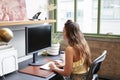 Young white woman using a computer in an office, back view Royalty Free Stock Photo