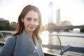 Young white woman wearing grey coat standing on Millennium Bridge, London, looking to camera smiling Royalty Free Stock Photo