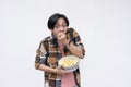 A young wide-eyed asian man voraciously stuffing his mouth with popcorn while watching a movie. Isolated on a white background